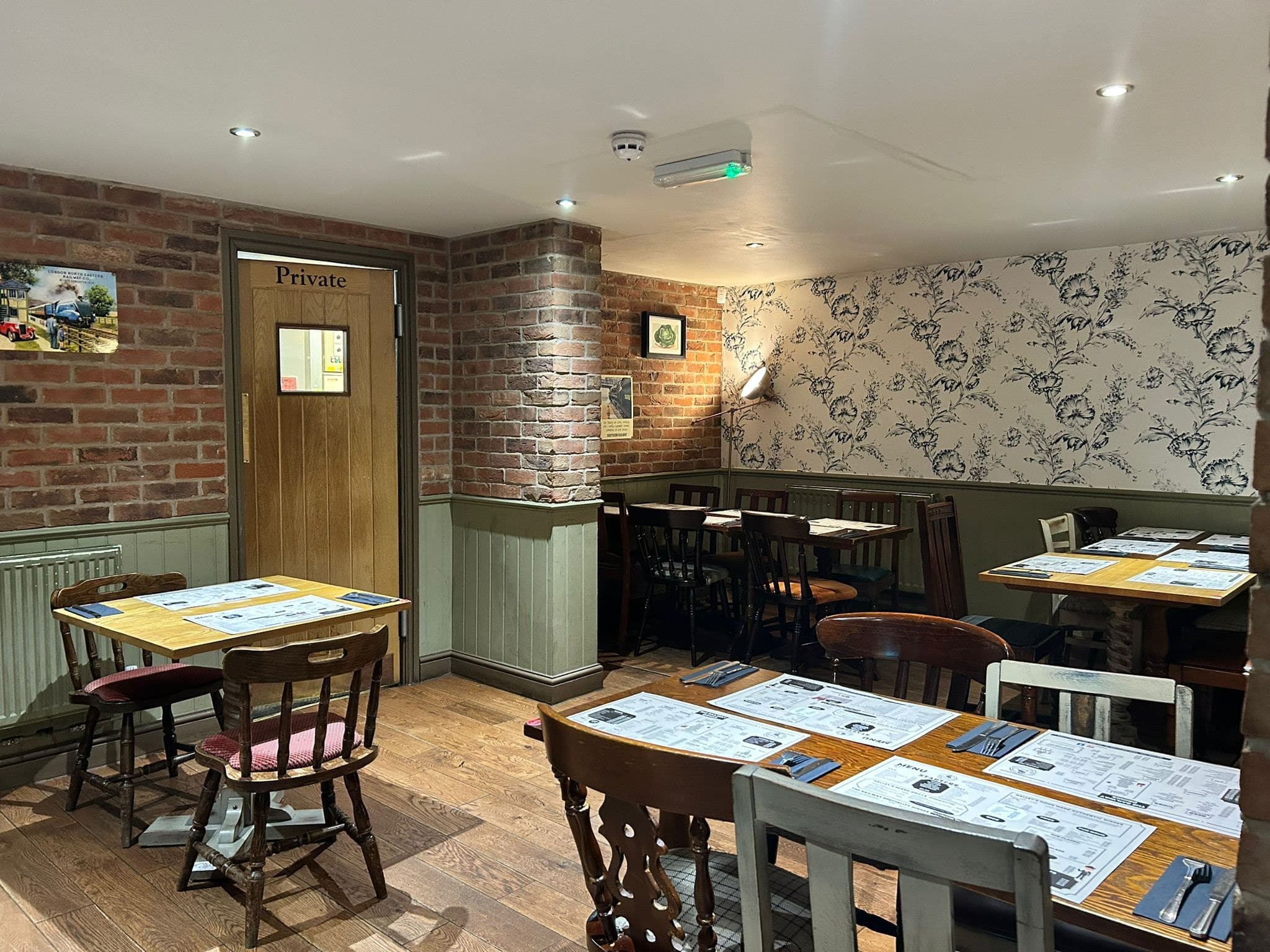 Dining area at The Railway with brick walls and wooden tables laid for a meal